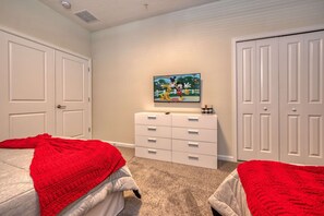 Une chambre avec deux lits, une commode, un téléviseur fixé au mur et un placard.