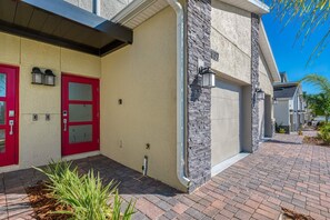 A modern building with a beige facade, red doors, and a stone accent wall.
