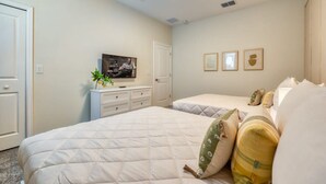 Una camera da letto con due letti, una televisione e un comò.