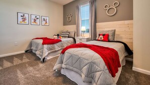 Een slaapkamer met twee bedden, een raam met gordijnen en wanddecoratie.