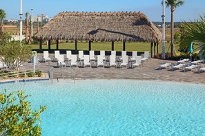 A pool area with lounge chairs and a thatched-roof structure.