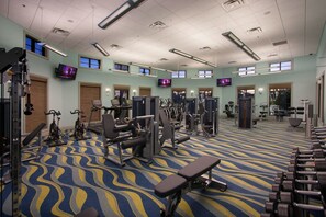 A spacious gym with various exercise equipment, large windows, and a patterned carpet. - Chic 3BR Modern Condo Spacious Mickey-themed (Davenport)