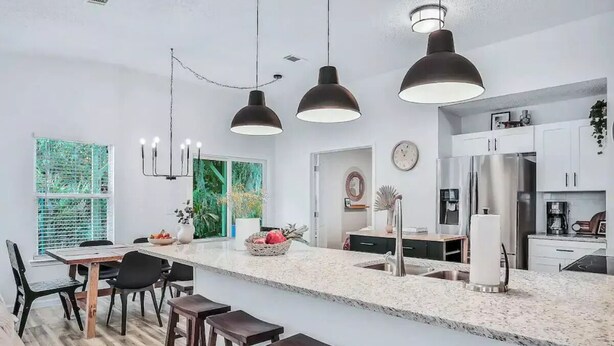 A modern kitchen with a large island, pendant lights, and stainless steel appliances. - Peaceful Escape in Atlantic Beach (Atlantic Beach)