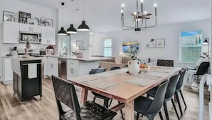 A modern kitchen with white cabinets, a central island, and pendant lighting. - Peaceful Escape in Atlantic Beach (Atlantic Beach)