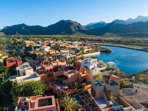 A coastal resort with multiple buildings, a marina, and mountains in the background.