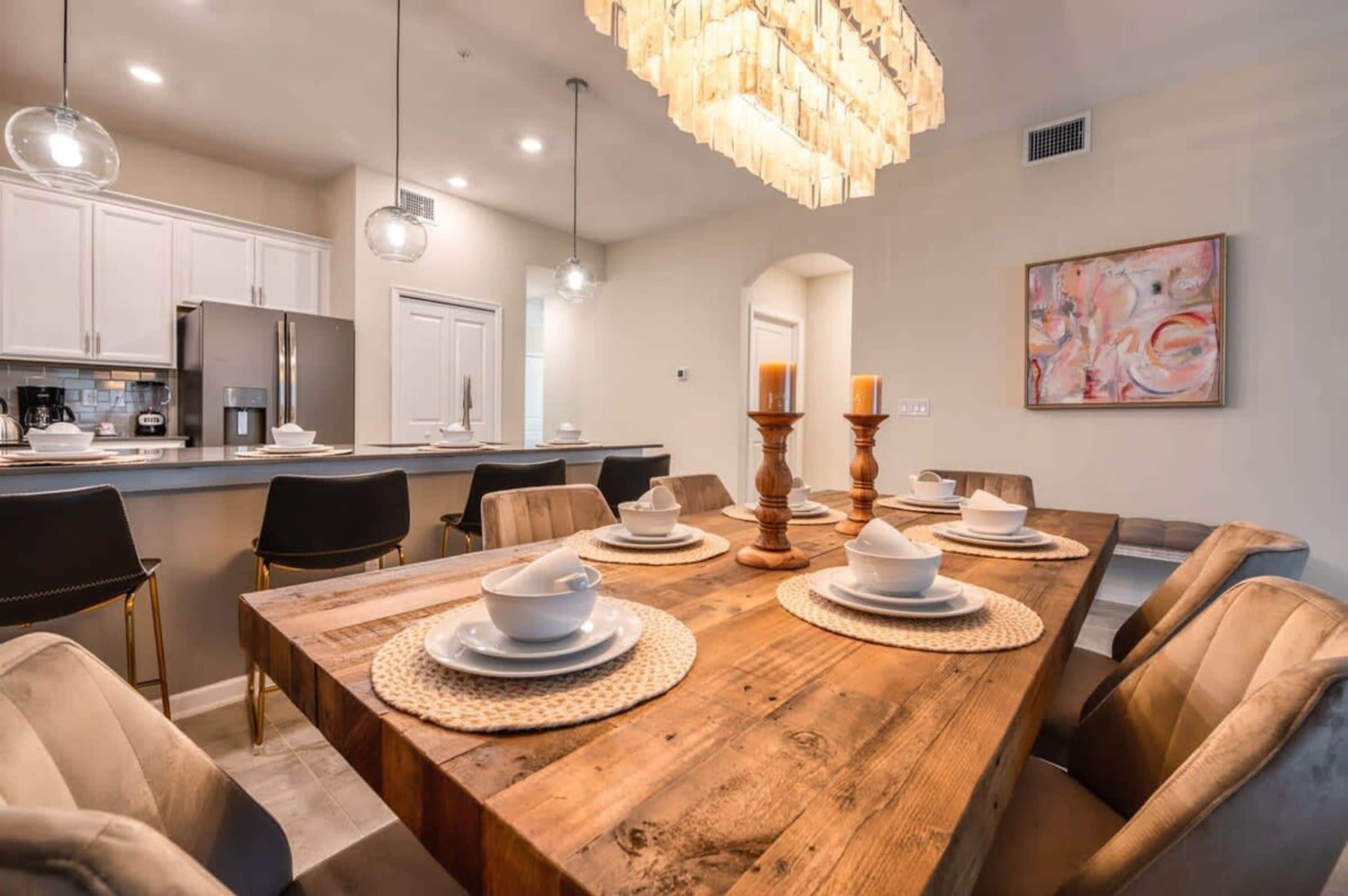 A modern dining area with a wooden table set for six, surrounded by leather chairs.