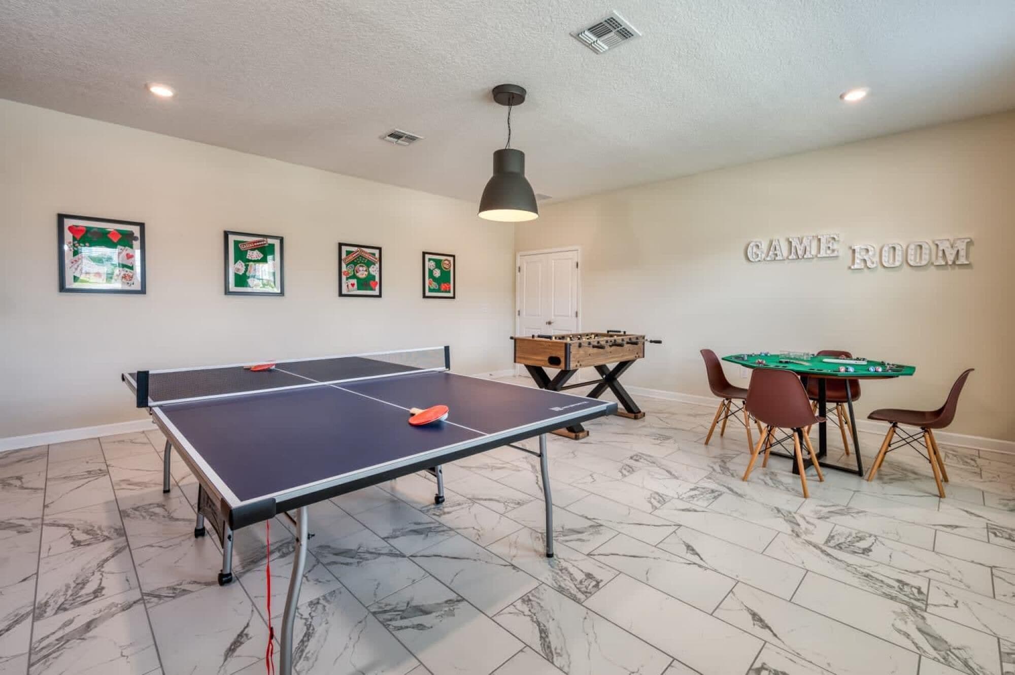 A game room with a ping pong table, foosball table, and pool table.