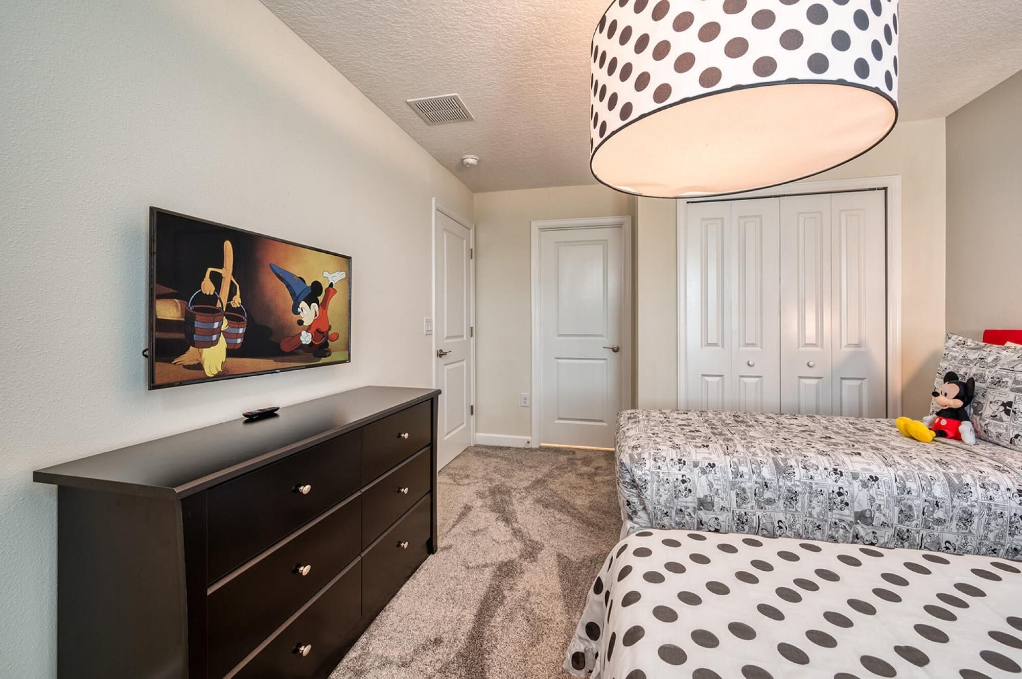 A bedroom with a bed, a dresser, a television, and a door.
