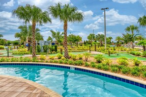 Relax by the serene pool surrounded by lush greenery and palm trees.
