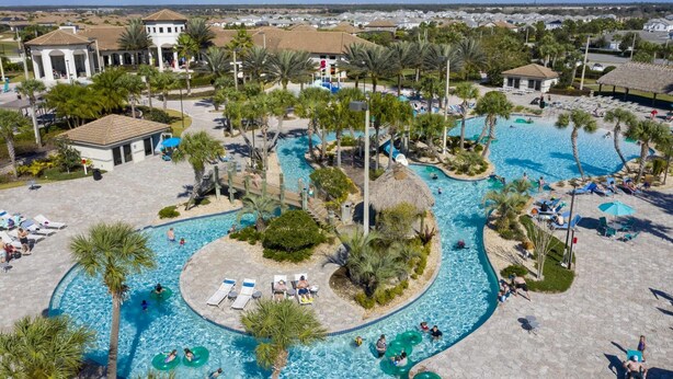A large outdoor swimming pool with multiple lanes, surrounded by palm trees and lounge chairs. - Comfy Themed Home Private Pool Prime Location (Davenport)