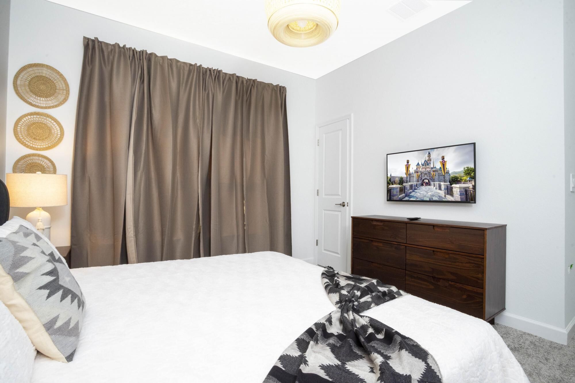 A bedroom with a bed, a TV on a dresser, and curtains.