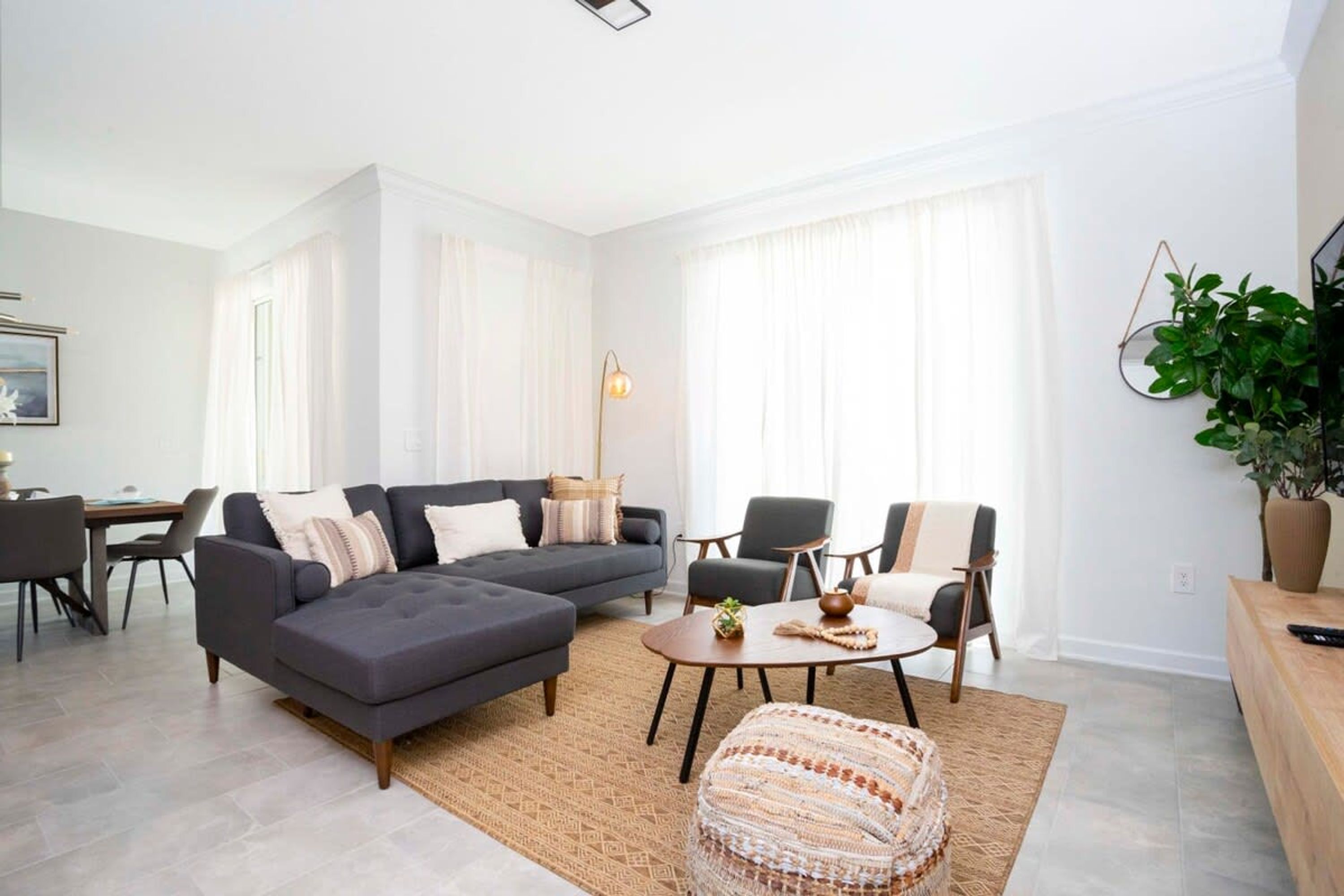 A modern living room with a sectional sofa, a round coffee table, and a dining area with a table and chairs.