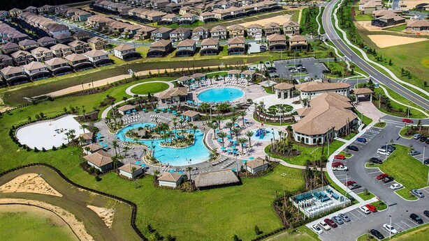 Eine Vogelperspektive eines Resorts mit mehreren Schwimmbecken, einem Parkplatz und Wohnhäusern.