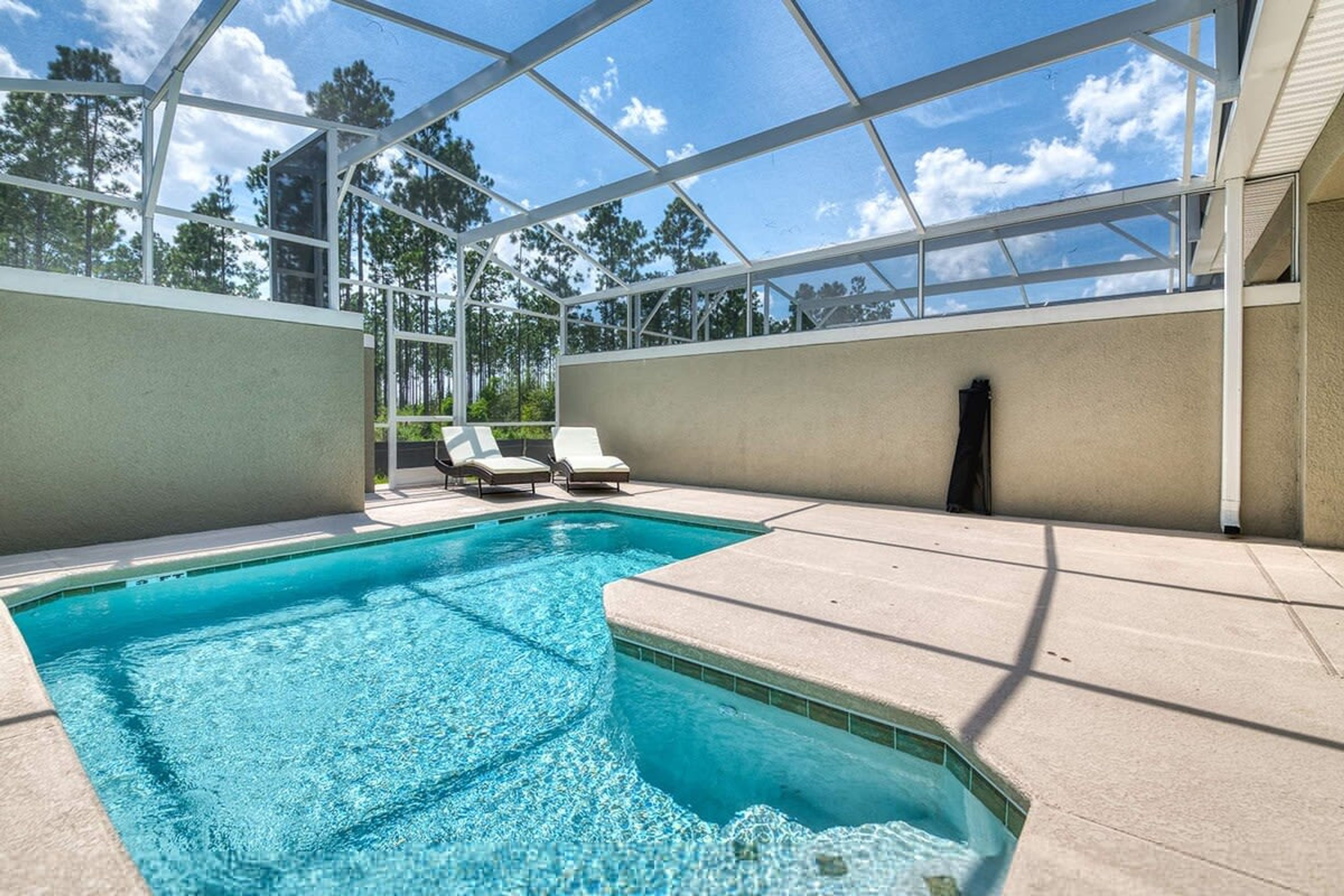 A swimming pool with clear blue water, surrounded by a covered area with white walls and a glass ceiling.