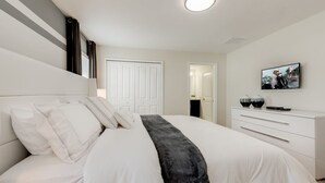 A modern bedroom with a large bed, a dresser, and a television on the wall. - Cozy Home Prime Disney Parks Location (Kissimmee)