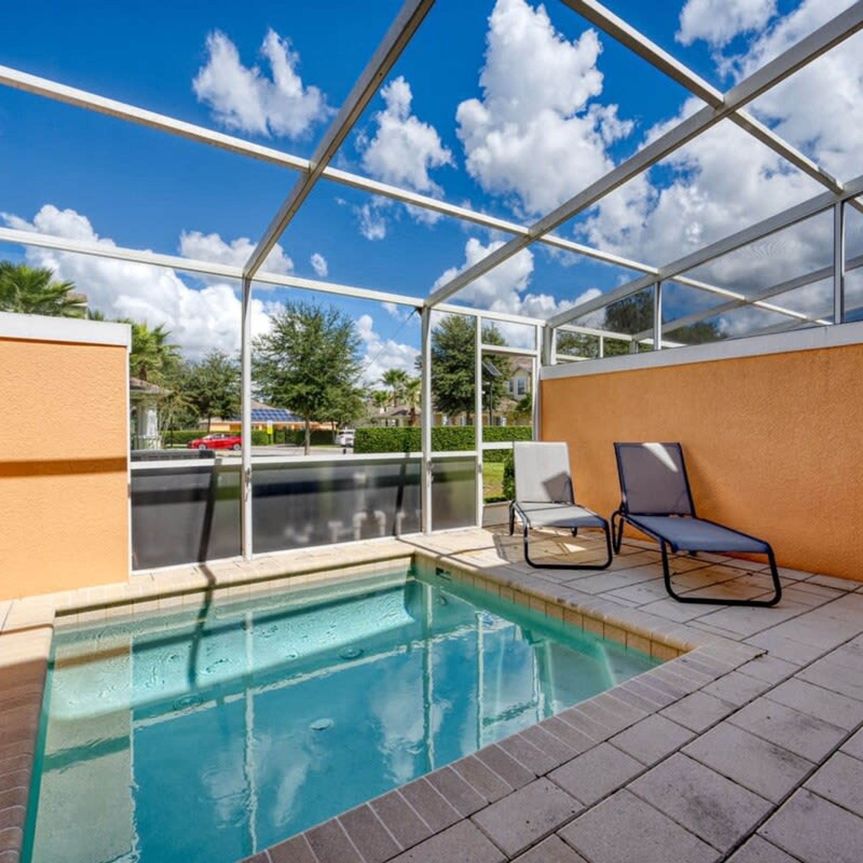 Piscina ao ar livre coberta com duas espreguiçadeiras e vista para os arredores.