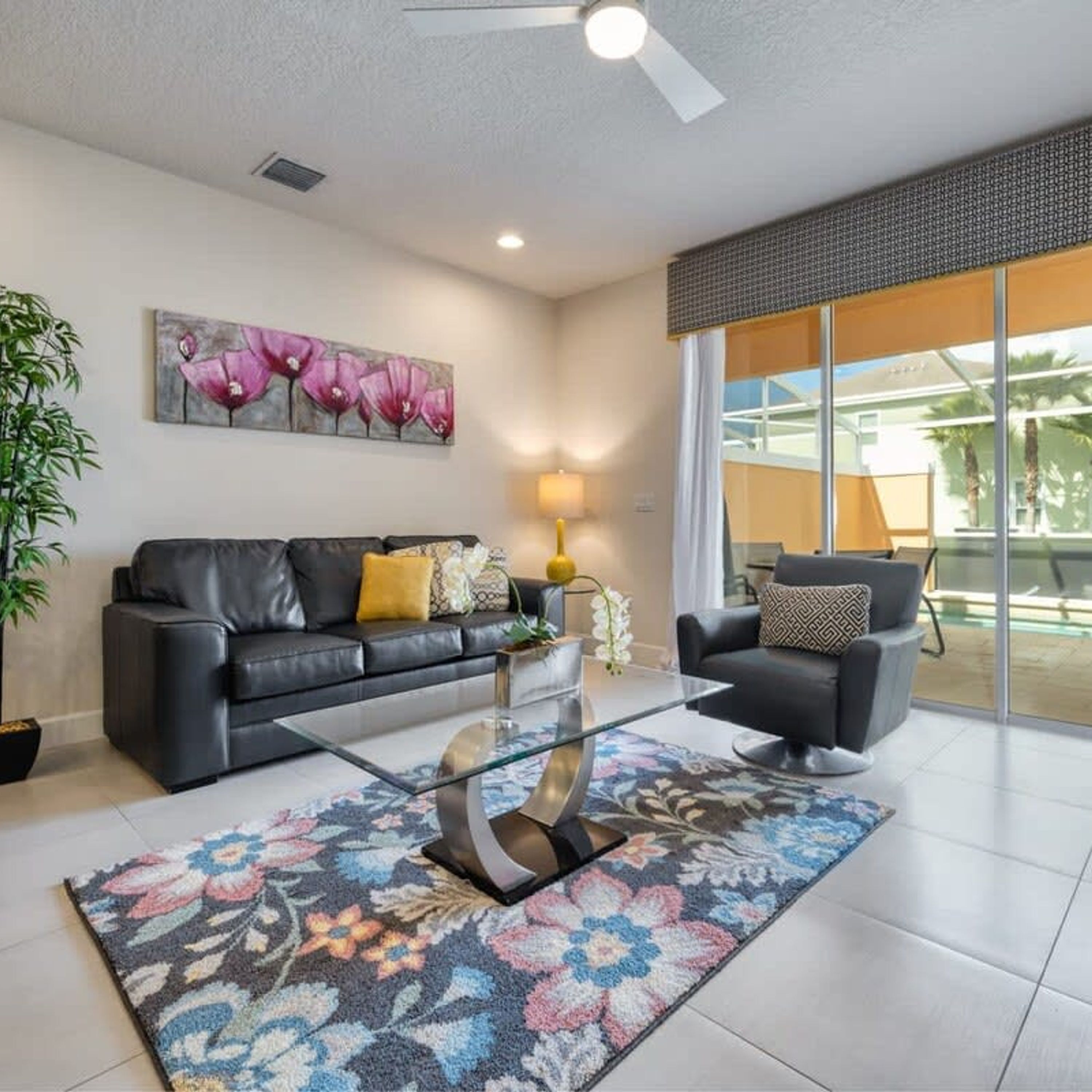 A modern living room with a leather sofa, a glass coffee table, and a colorful rug.