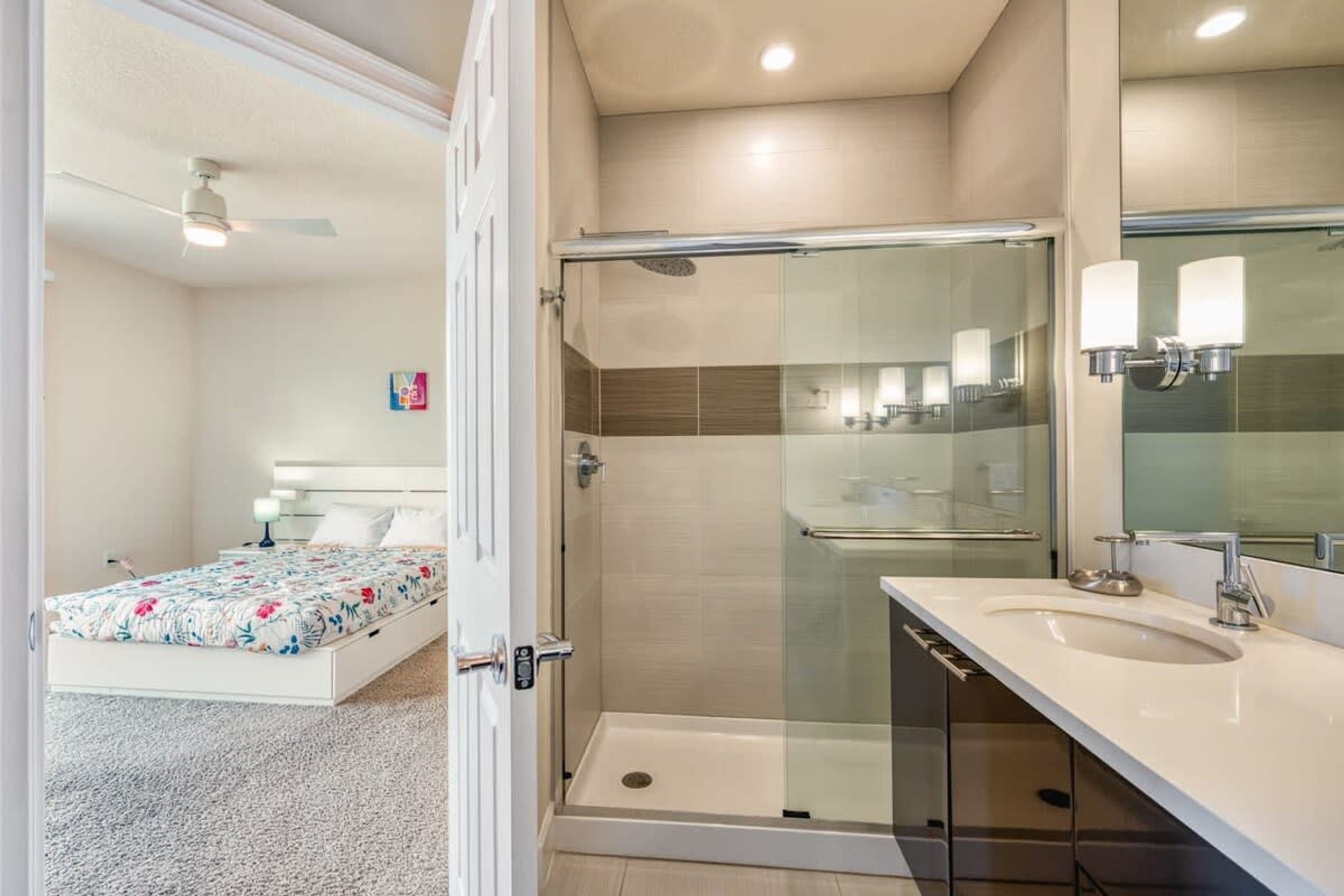 A modern bathroom with a glass shower enclosure, a white sink, and a large mirror.