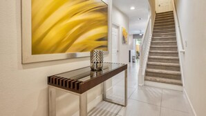 Un pasillo con una escalera, una obra de arte enmarcada y una consola con un florero.