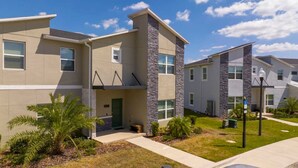 A modern apartment building with a flat roof, stone accents, and a well-maintained lawn. - Cozy Getaways - Spacious Ideal Location (Davenport)