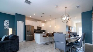A modern kitchen with white cabinets, a central island, and bar stools. - Cozy Getaways - Spacious Ideal Location (Davenport)