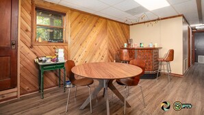 A room with a wooden herringbone wall, a round wooden table with four chairs, a small green side table, and a brick accent wall. - Sparkling Bear Lodge | Epic views! | Touch the stars (Mount Jackson)