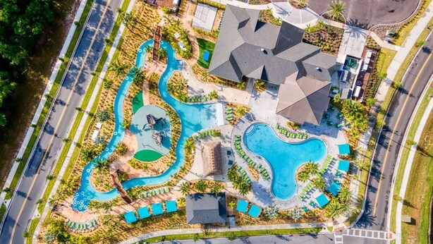 Vista aérea de un resort con varias piscinas, una fuente serpenteante y un edificio grande con techo inclinado.