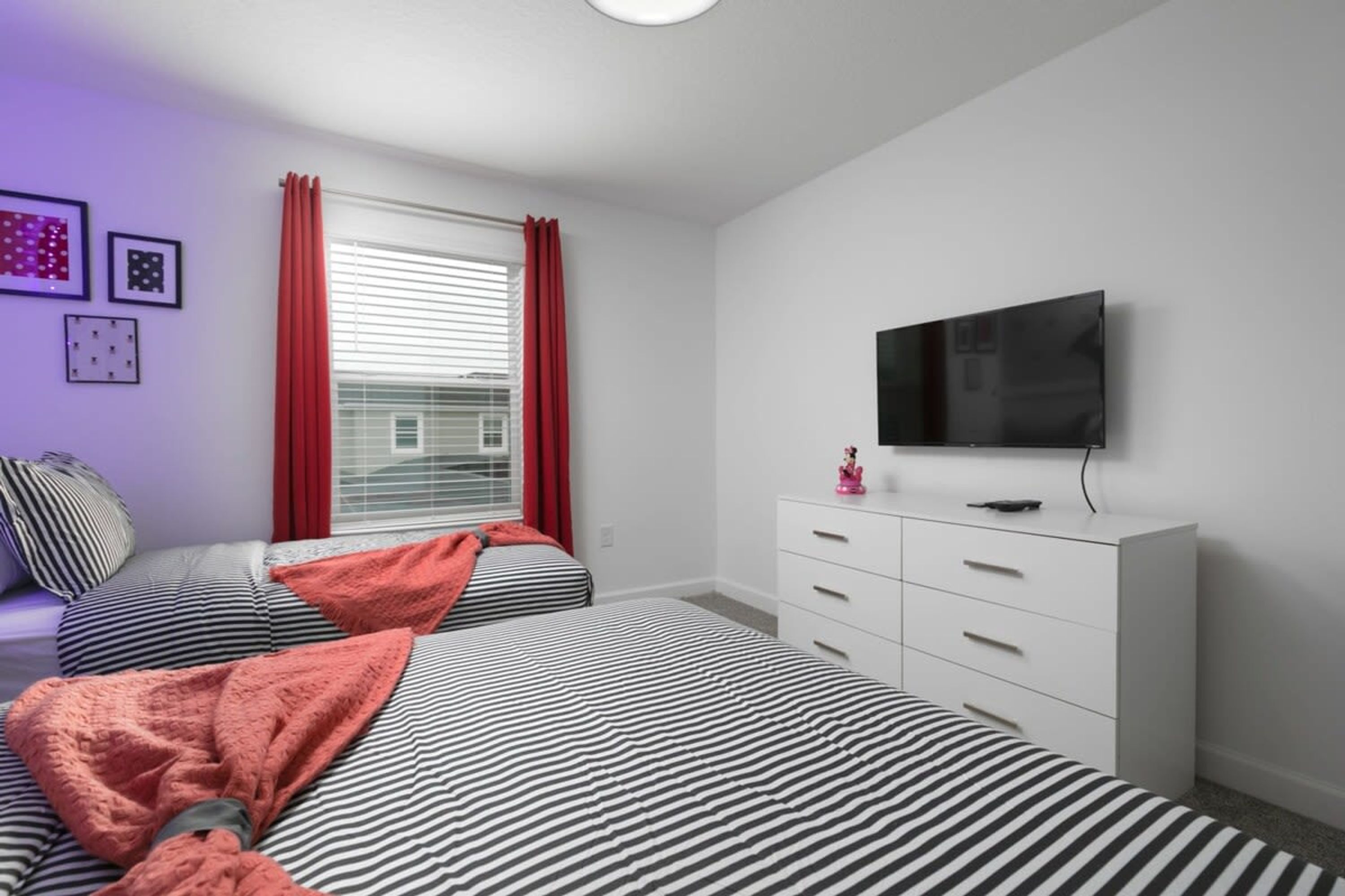 A bedroom with two beds, a TV, and a dresser.
