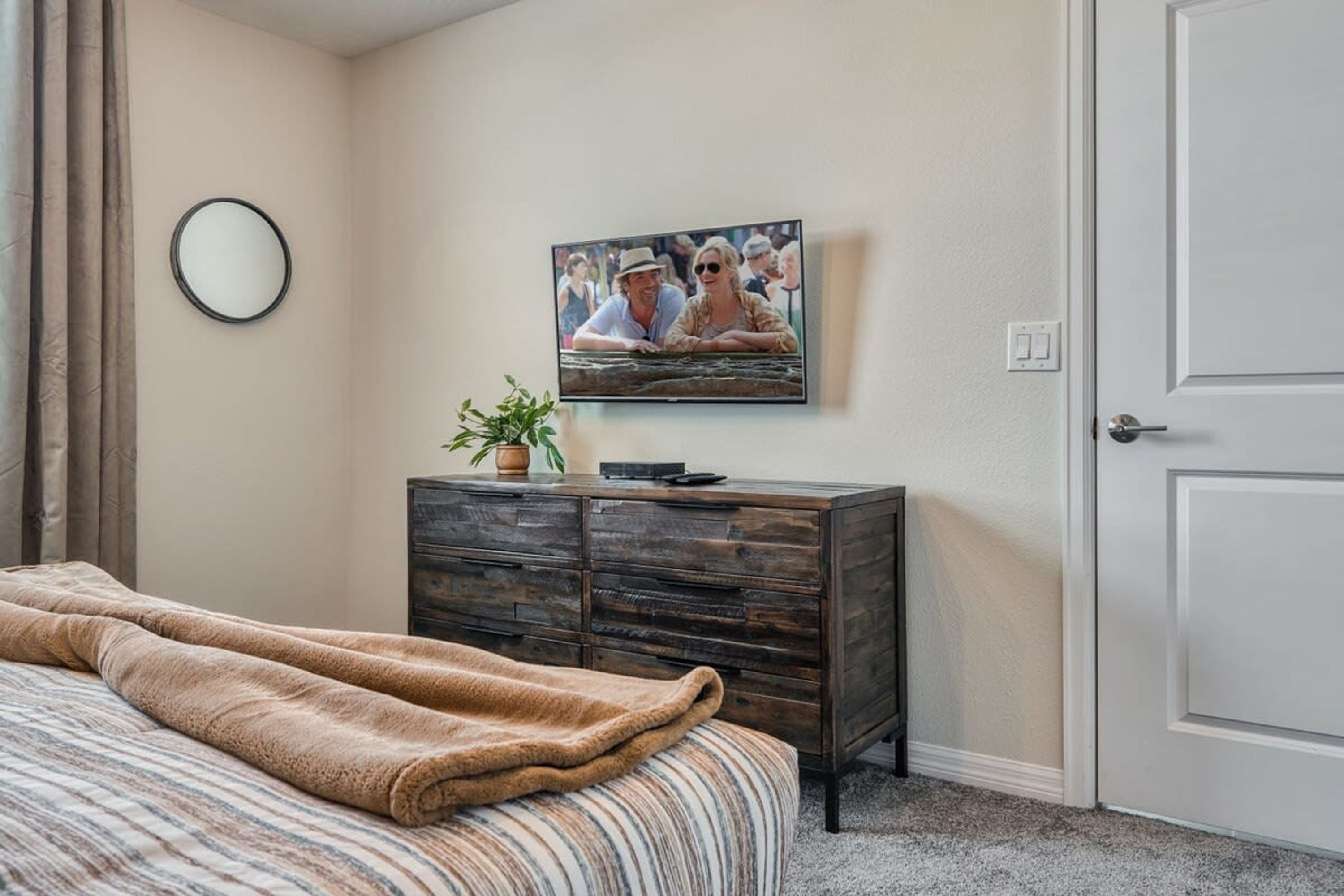 Ein Schlafzimmer mit einem Bett, einem Schminktisch, einem Fernseher und einer Tür.