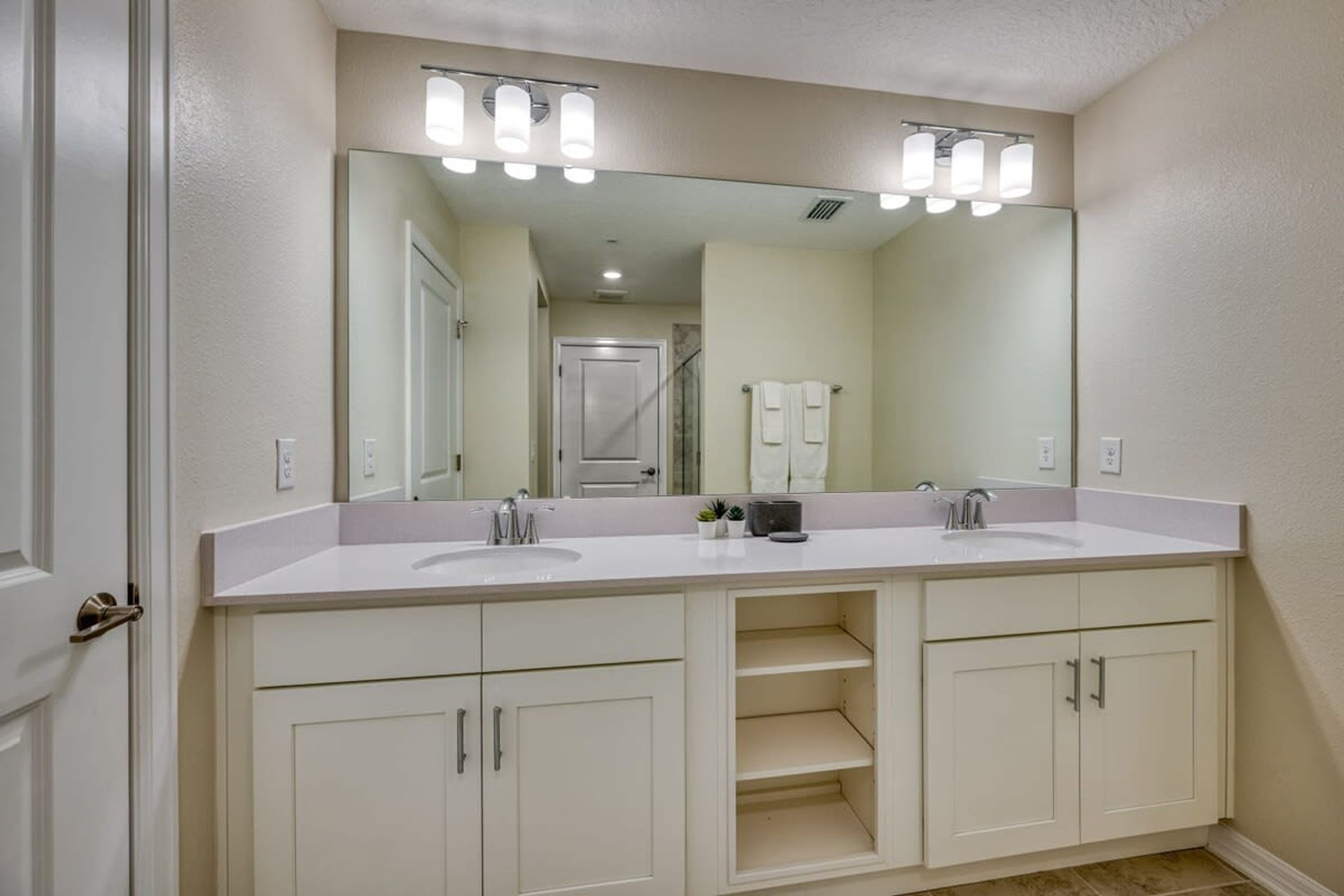 A bathroom with two sinks, a large mirror, and a vanity with cabinets.
