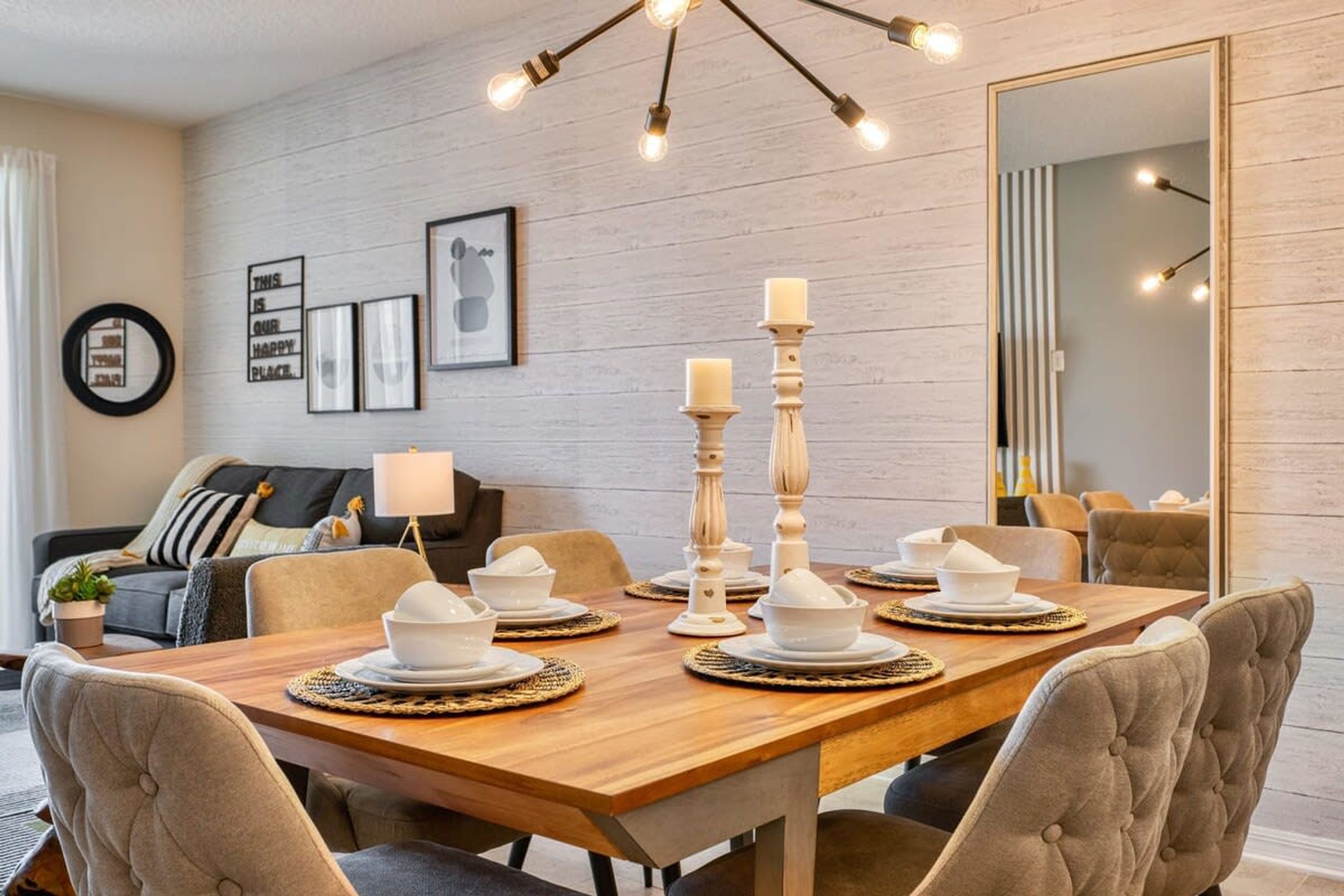 A dining area with a wooden table set for four, surrounded by upholstered chairs.