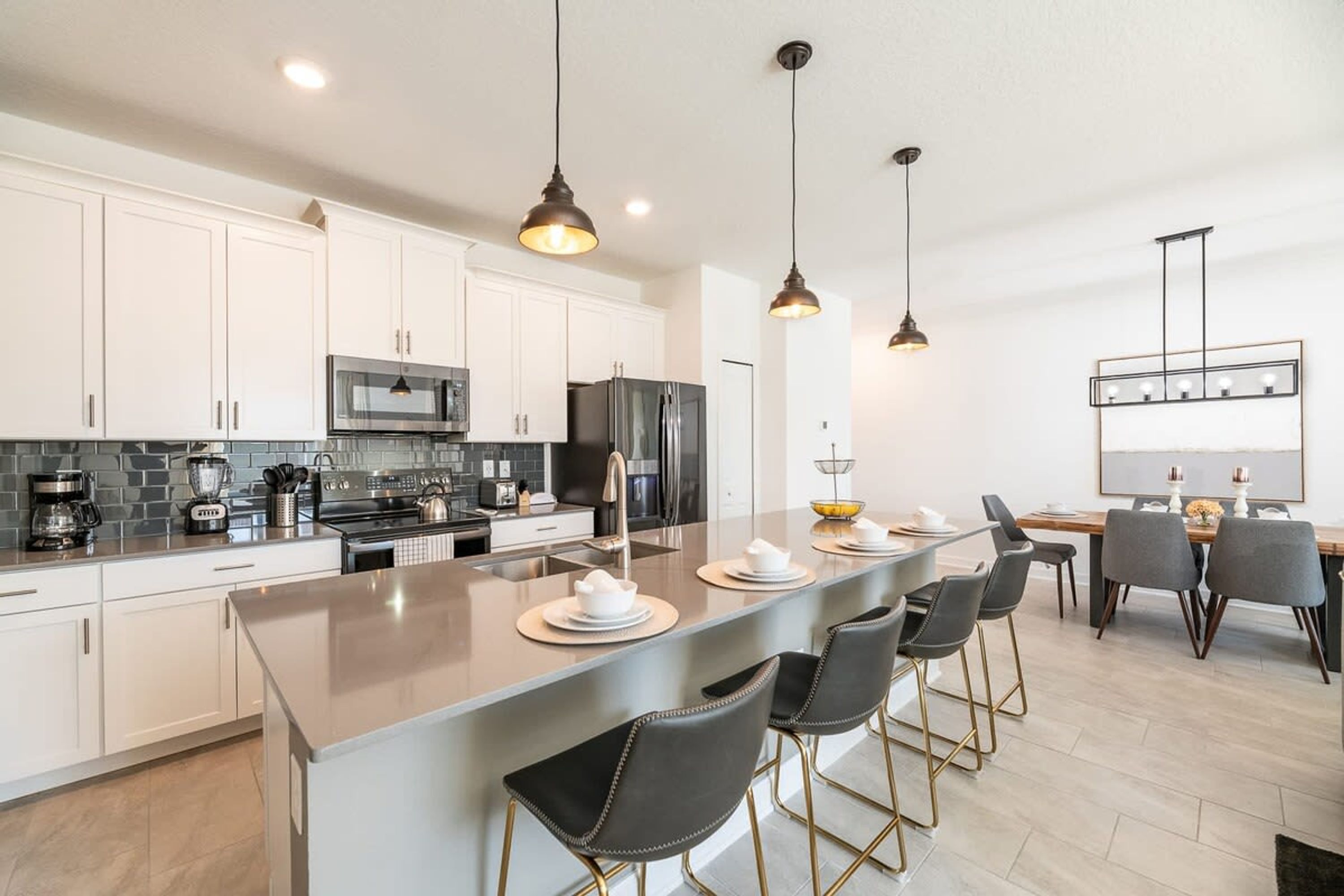A modern kitchen with white cabinets, stainless steel appliances, and a central island with bar stools.