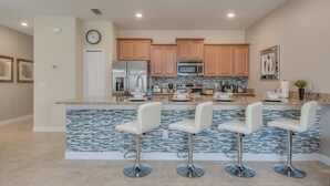A modern kitchen with a central island, stainless steel appliances, and a tiled backsplash. - Prime Locale - Vacation Paradise (Kissimmee)