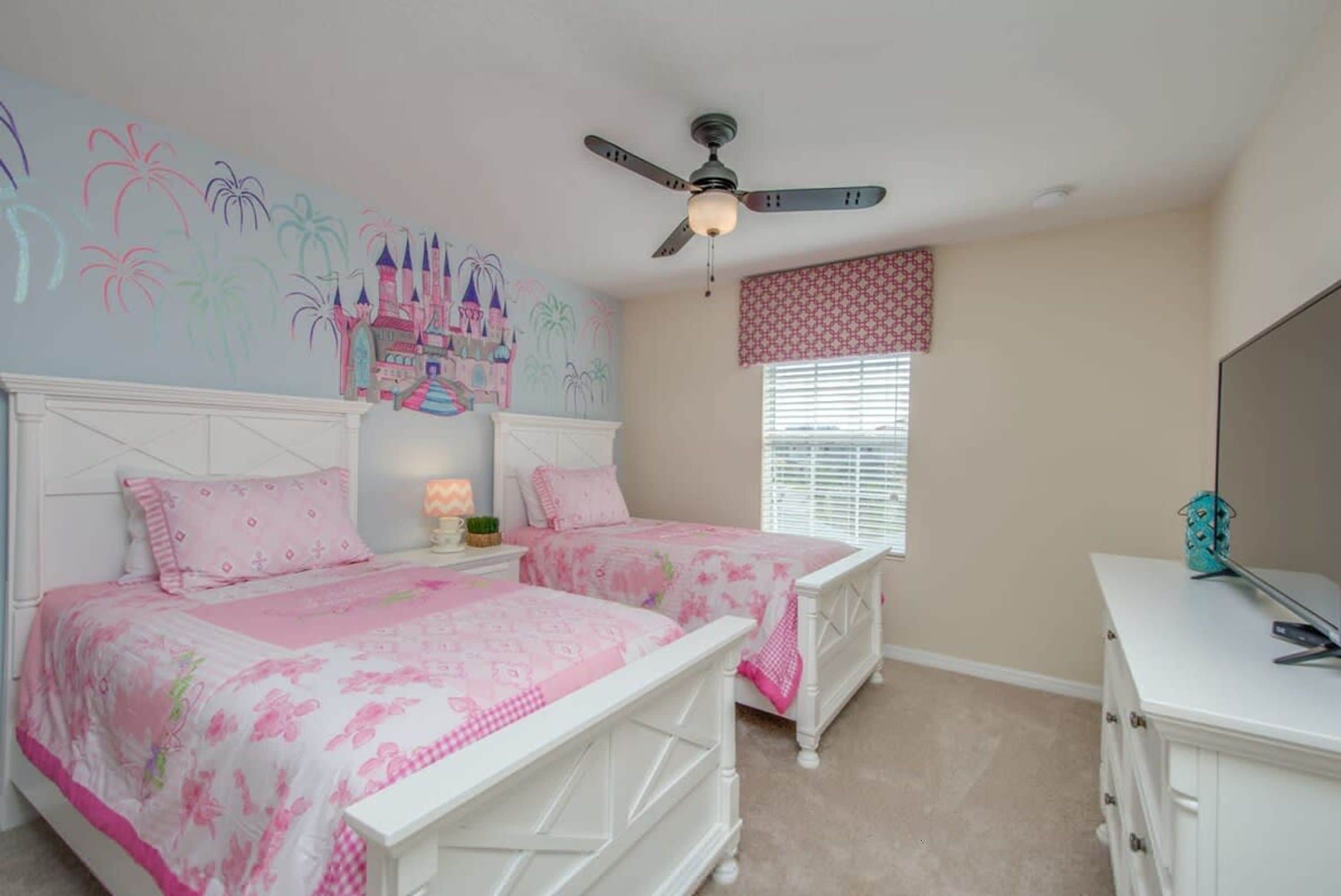 A bedroom with two beds, a ceiling fan, a mural on the wall, and a window with blinds.