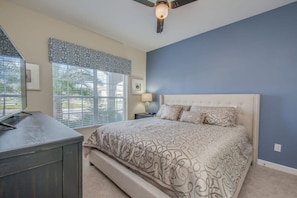 A bedroom with a bed, a desk, a ceiling fan, and a window with blinds. - Prime Locale - Vacation Paradise (Kissimmee)