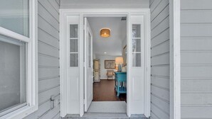 En hall som leder till ett rum med en blå stol och en lampa.
