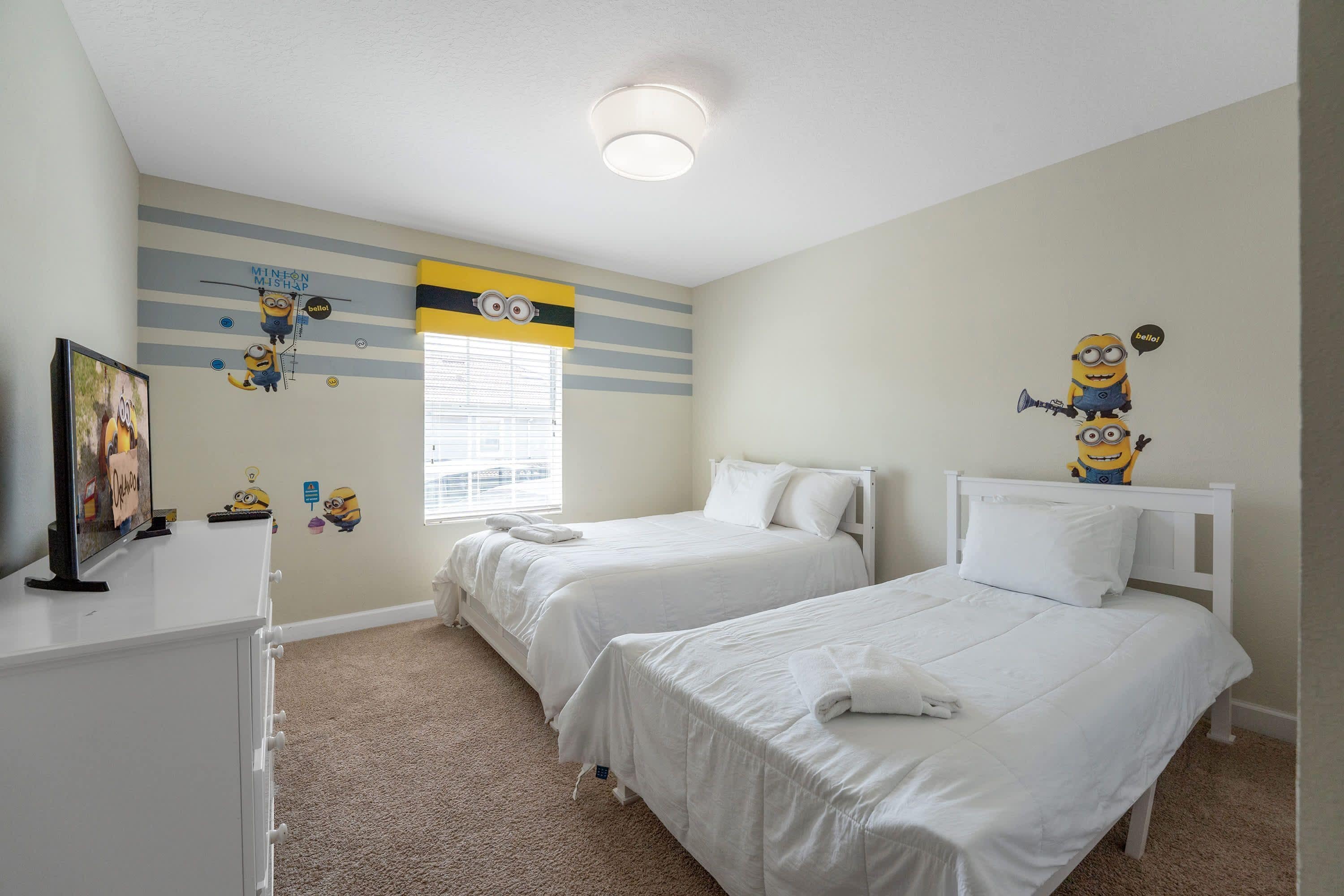 A bedroom with two beds, a desk, and a window with blinds.