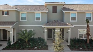 A residential building with a tiled roof, multiple windows, and a small front porch.