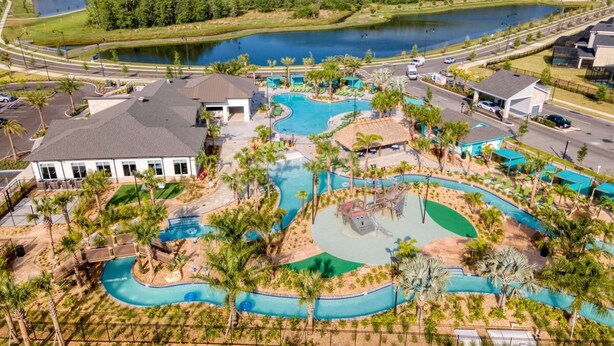 An aerial view of a resort with a swimming pool, palm trees, and a lake. - Spacious Comfy Retreat Prime Location Amazing (Kissimmee)