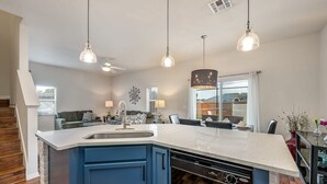 Een moderne keuken met een centraal eiland, blauwe kastjes en hanglampen.