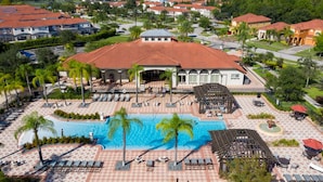 Een resort met een zwembad, palmbomen en een overdekt terras.