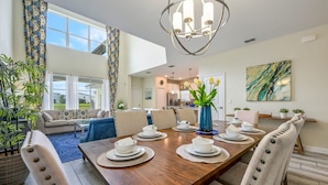 A spacious dining area with a wooden table set for six, surrounded by upholstered chairs. - Luxury Storey Lake Retreat - Spacious Disney-near (Kissimmee)
