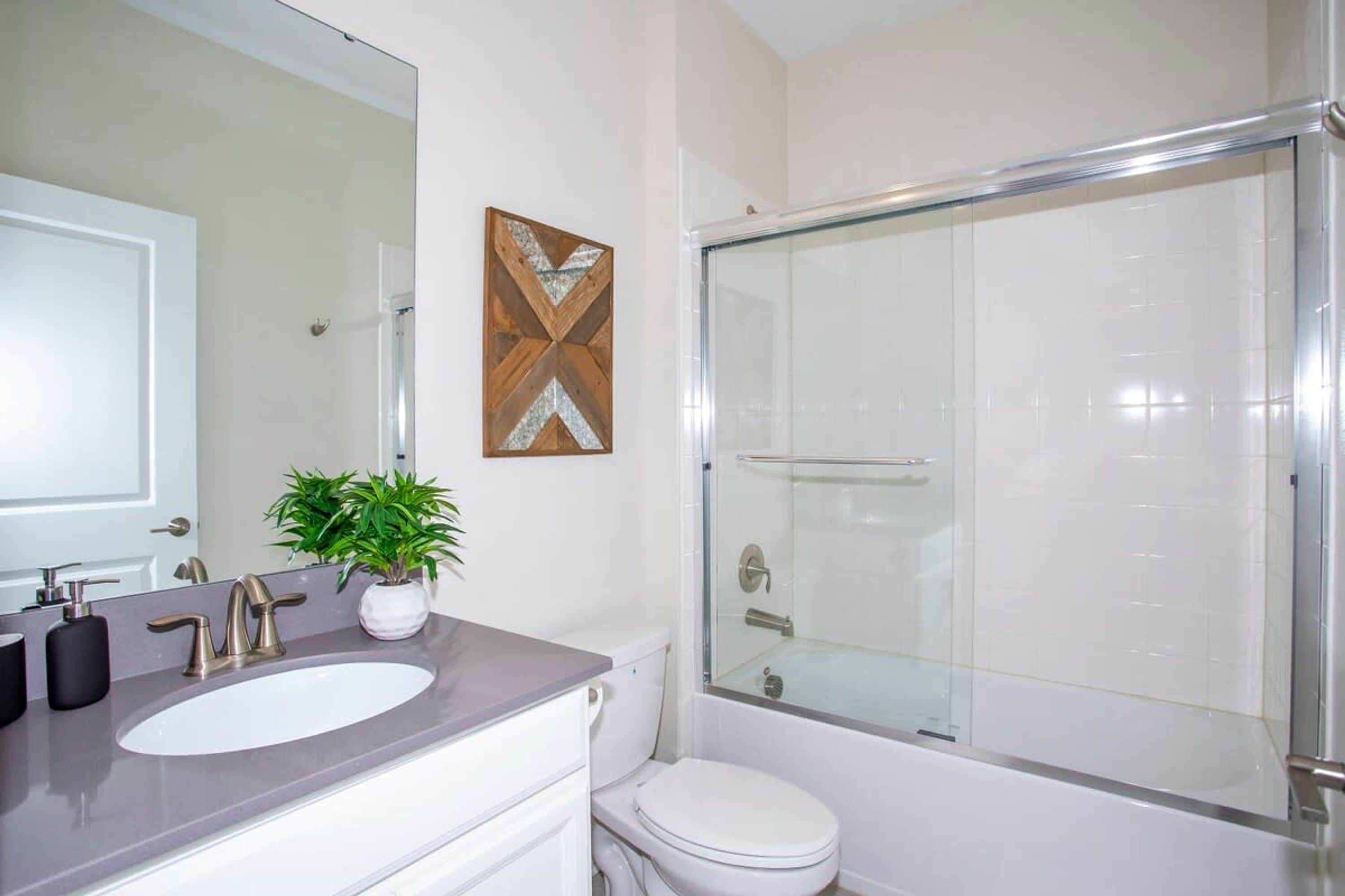 A bathroom with a white sink, a glass shower enclosure, and a white toilet.