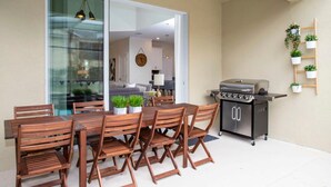 A patio with a wooden table and chairs, a grill, and potted plants. - Stunning 5BR Home - Your Dream Getaway (Kissimmee)