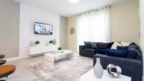 A modern living room with a white entertainment unit, a grey sofa, and a coffee table. - Themed Bedrooms Private Pool Amazing Location - Super Cute Home (Davenport)