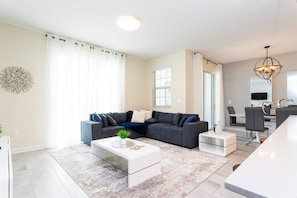 Un salon moderne avec un canapé d’angle, une table basse et un coin repas comprenant des chaises et une table.