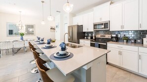 A modern kitchen with white cabinets, stainless steel appliances, and pendant lighting. - Themed 4BR Home-mickey Star Wars Pool Spacious (Kissimmee)