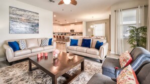 A living room with two sofas, a coffee table, and a ceiling fan. - Stunning Home Private Pool Great Location (Kissimmee)