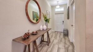 A hallway with a wooden console table, a mirror, and a door at the end. - Stunning Home Private Pool Great Location (Kissimmee)