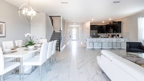 A modern kitchen with dark cabinets, a central island, and bar stools. - Getaway Delight-8 Bedrooms Pool Great Location (Davenport)